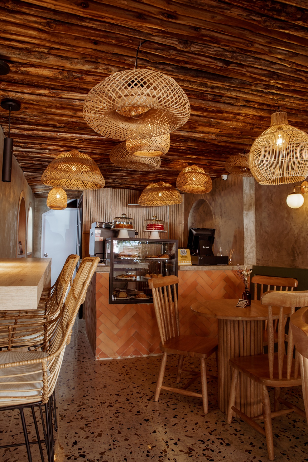 Interior de Amelier con techo de madera y lámparas de mimbre